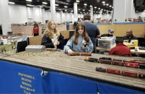 A group of people looking at model trains at a convention.