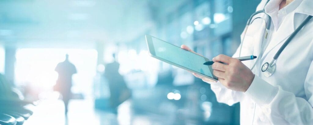 A doctor is holding a tablet in his hand.