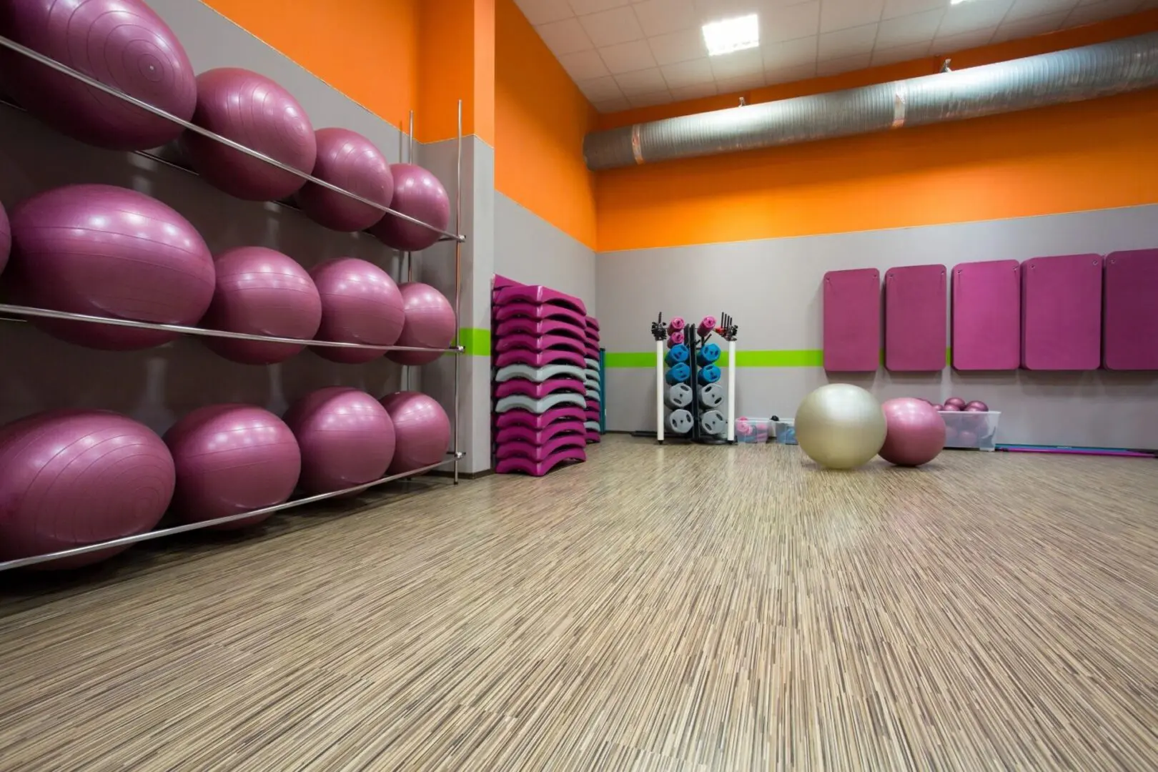 A gym with pink and purple balls on the floor.