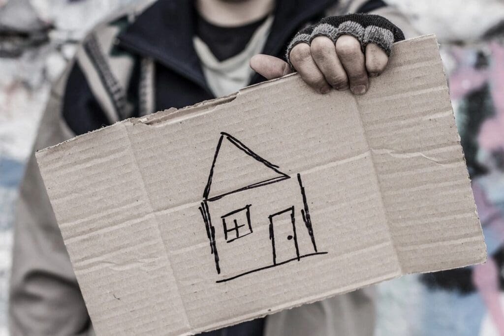 A man holding up a cardboard box with a house drawn on it.