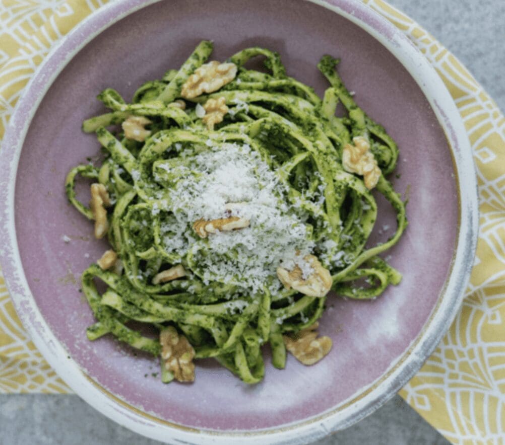A bowl of pesto pasta with walnuts and parmesan.