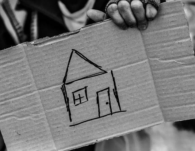 A person holding up a cardboard box with a drawing of a house.