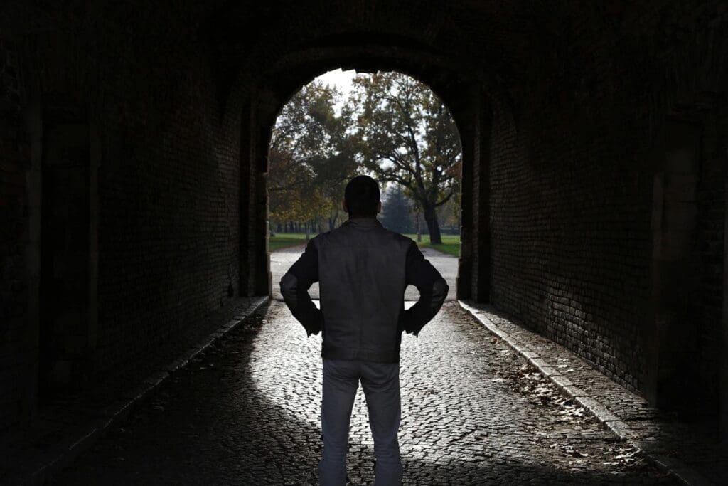 A man standing in a dark tunnel.