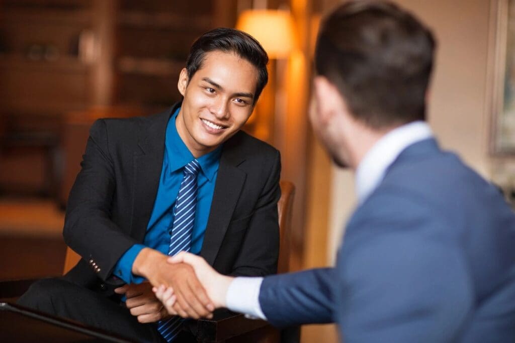 Asian businessman shaking hands with a man in a suit.