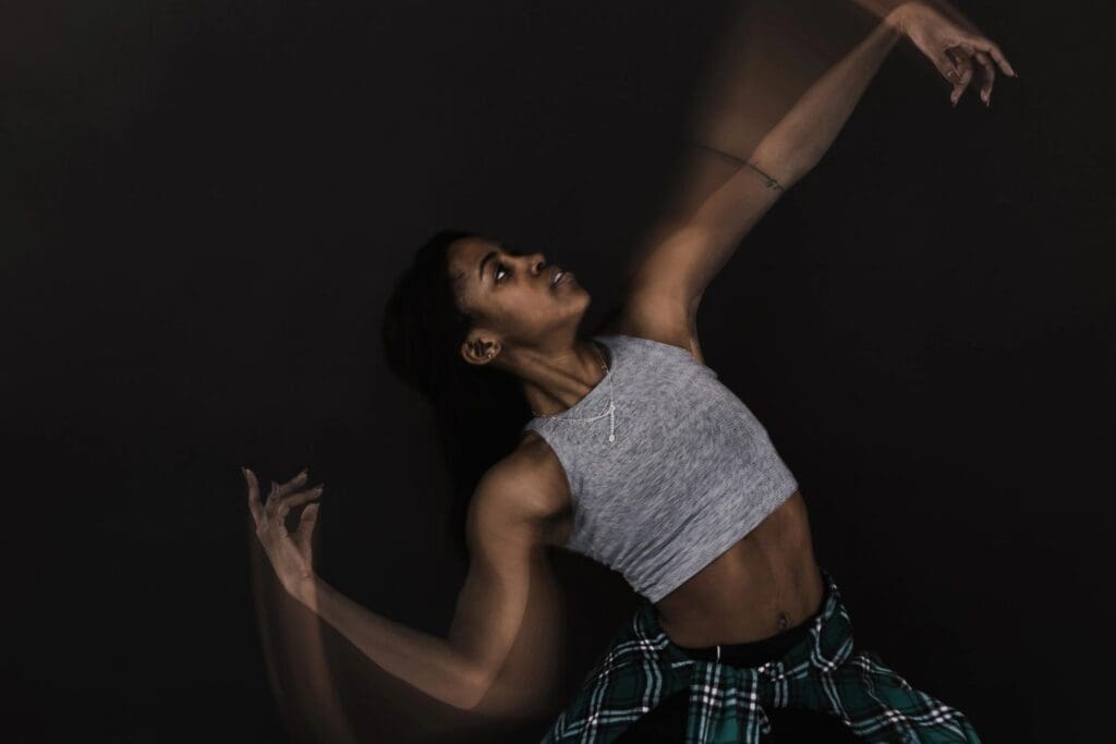 A woman in a plaid shirt is dancing on a black background.