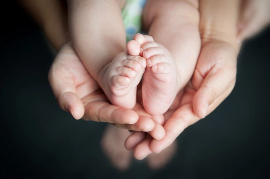 A pair of hands holding a baby's feet.