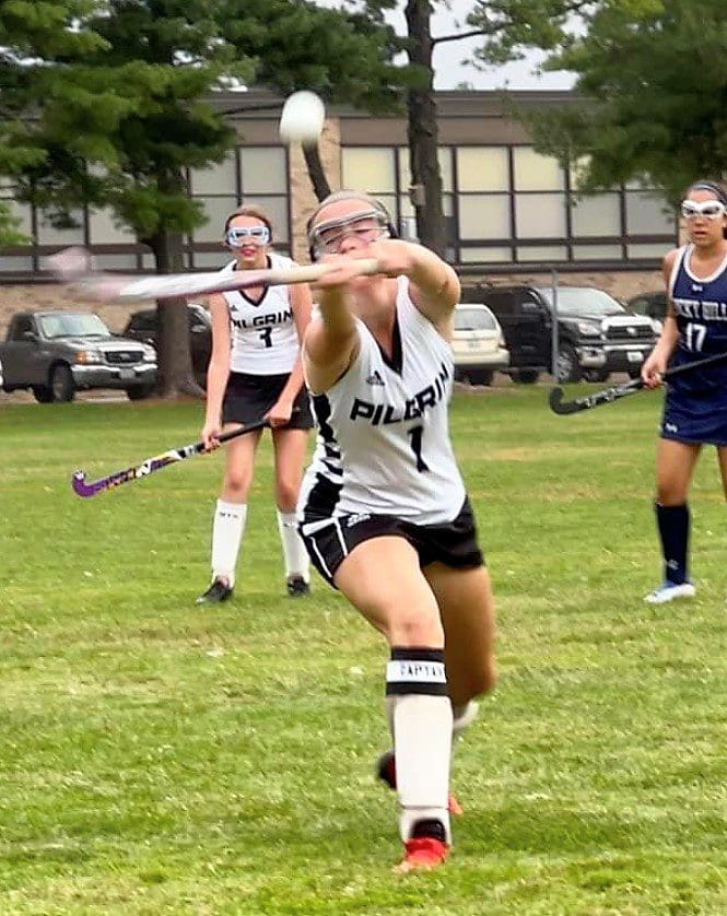 A field hockey player is trying to hit the ball.