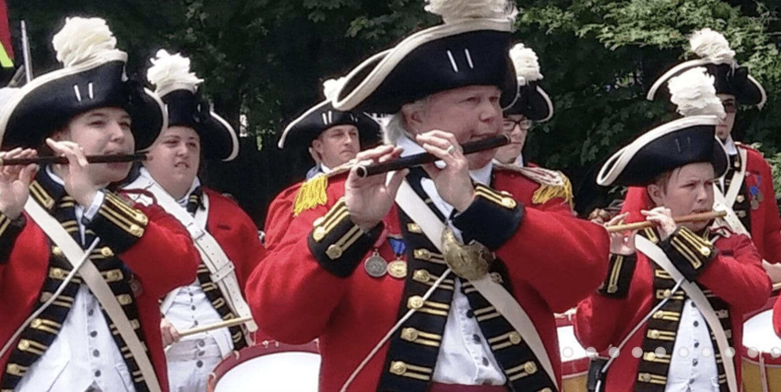 A group of men in red uniforms playing flutes.