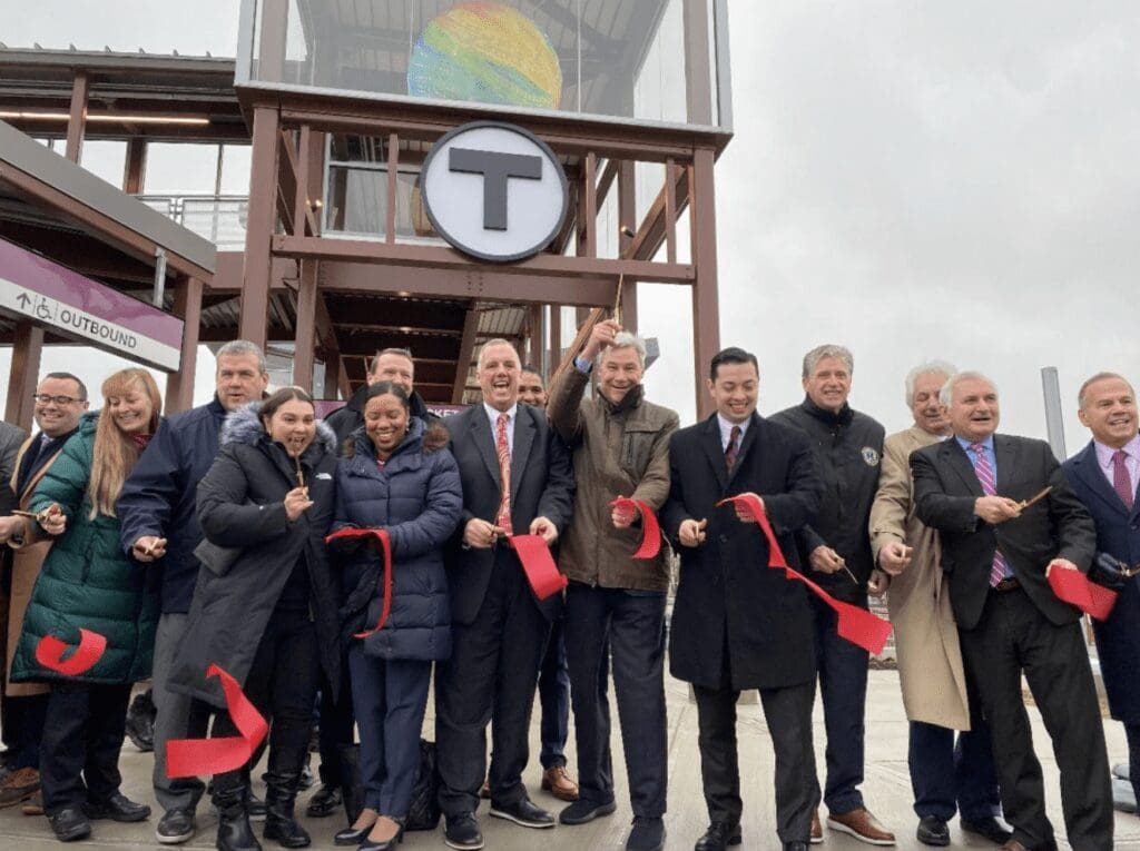 A group of people standing in front of a red ribbon.