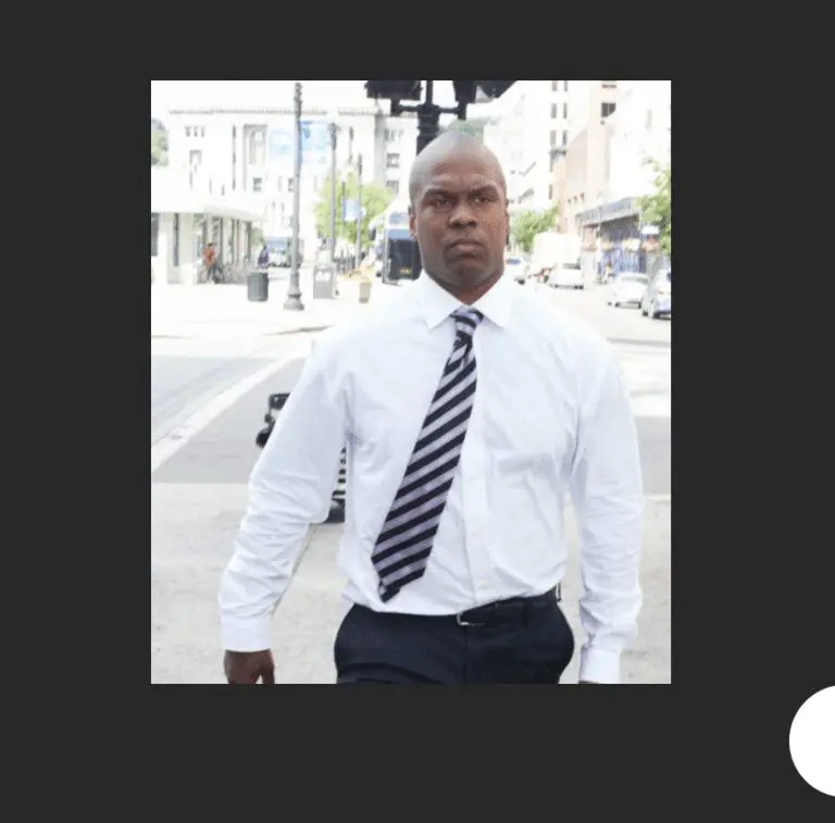 A man in a white shirt and tie walking down the street.
