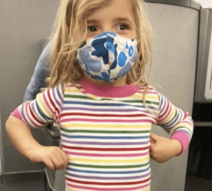 A little girl wearing a face mask in an airport.