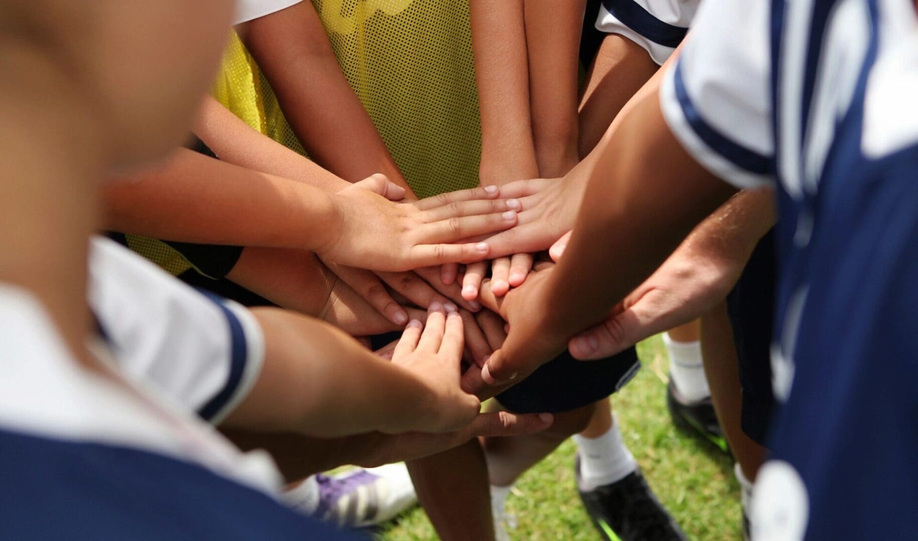 A group of soccer players putting their hands together.