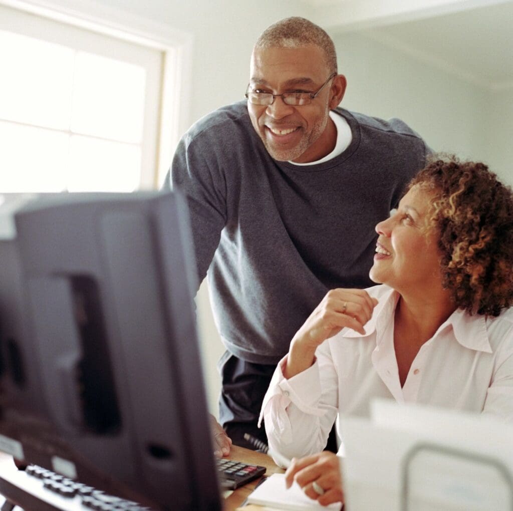 A man and woman looking at a computer screen.