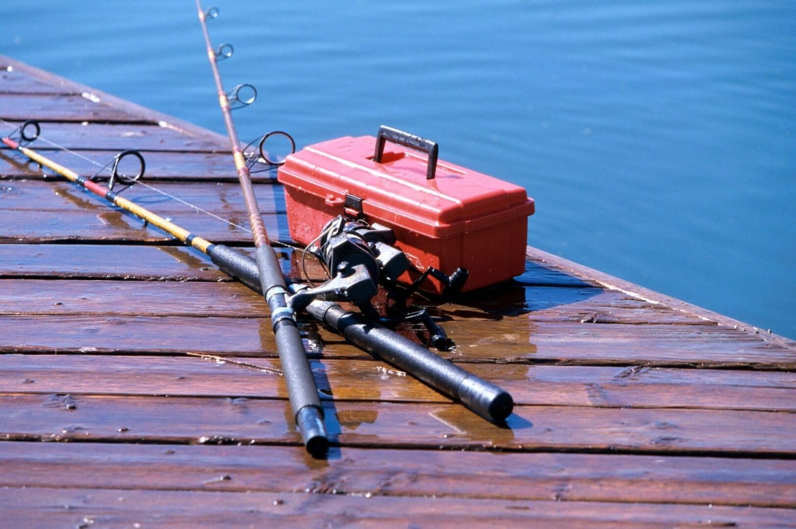 Two fishing rods and a fishing case on a wooden dock.