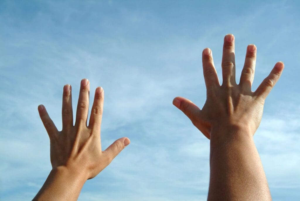 Two hands reaching up to the sky.