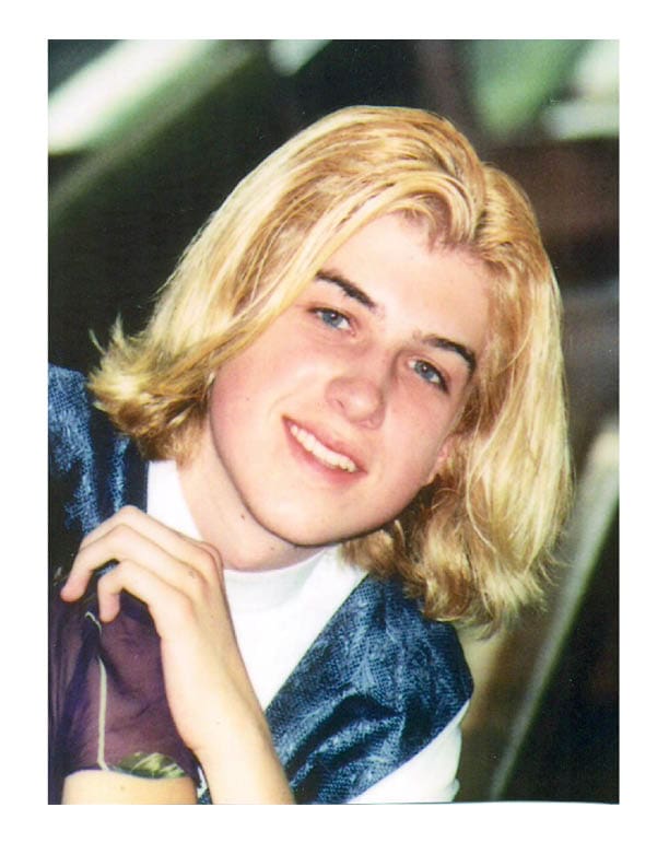 A young man with blonde hair is posing for a photo.