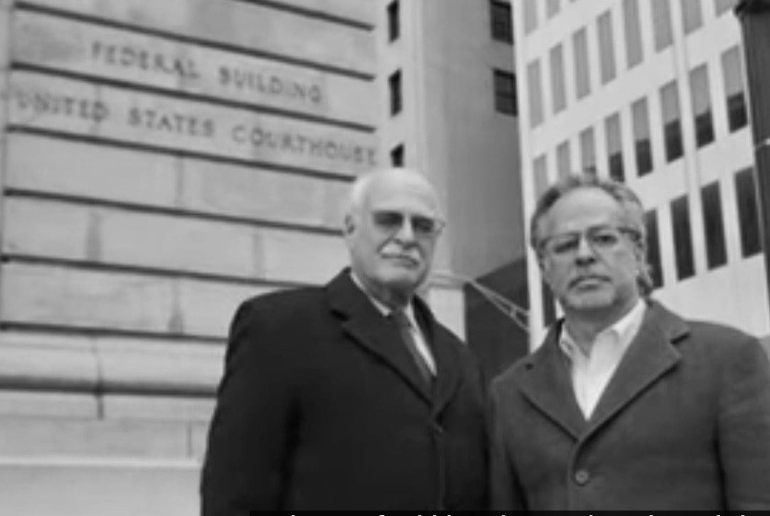 Two men in suits standing in front of a building.