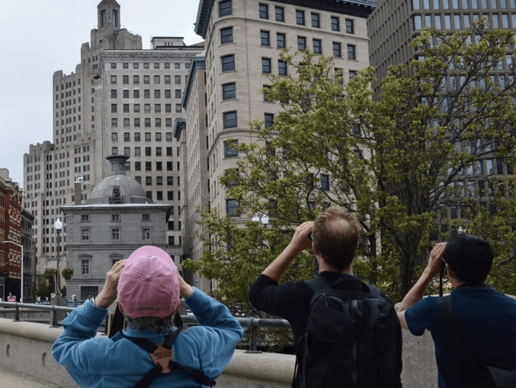 A group of people taking pictures of a city with tall buildings.