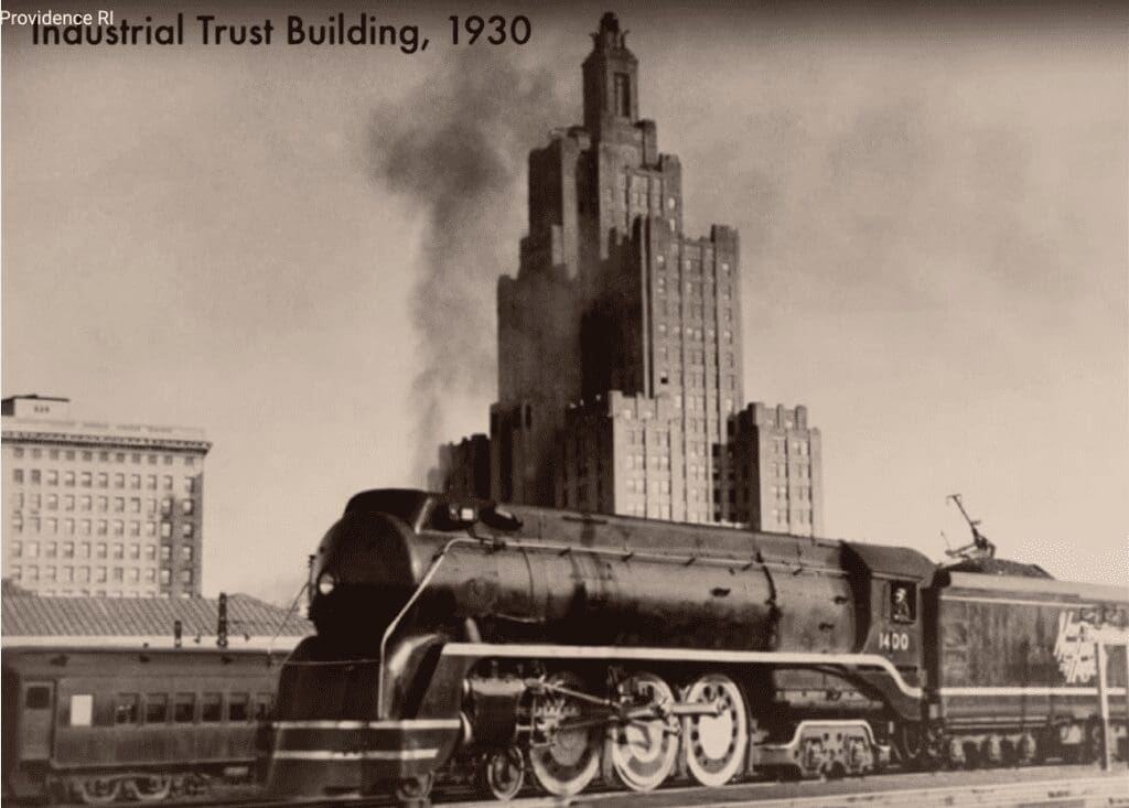 An old black and white photo of a train in front of a building.