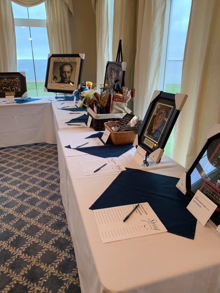 An auction table with a variety of framed pictures.