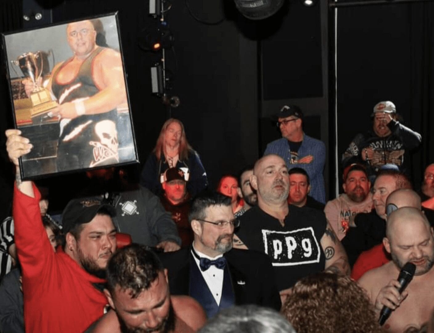 A group of people holding up a picture of a wrestler.