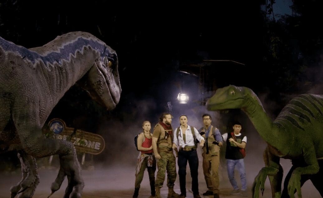 A group of people standing in front of a group of dinosaurs.