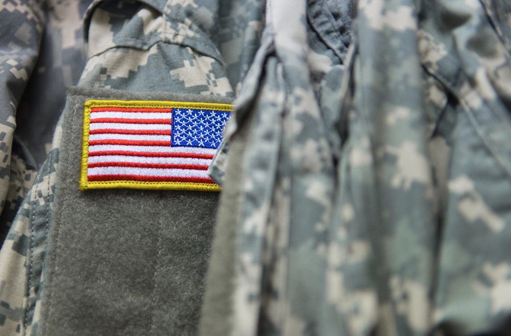 A close up of an american flag on a camouflage uniform.