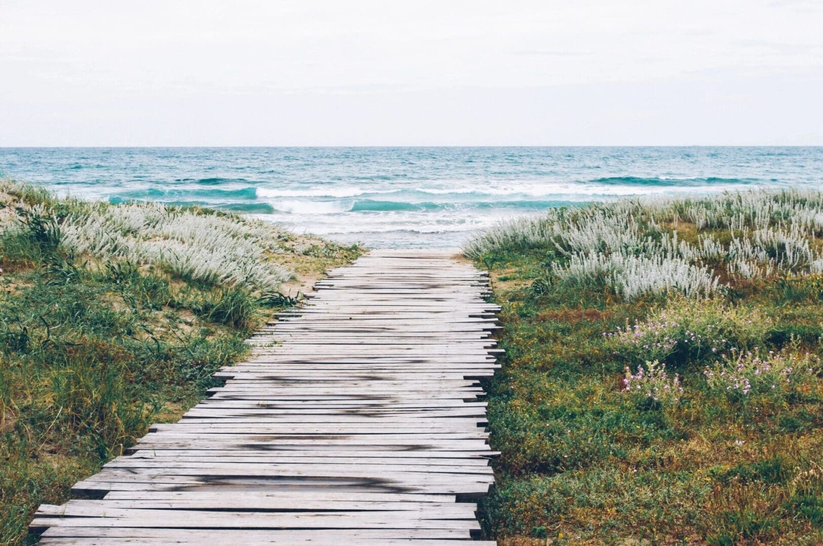 A wooden walkway leading to the ocean.
