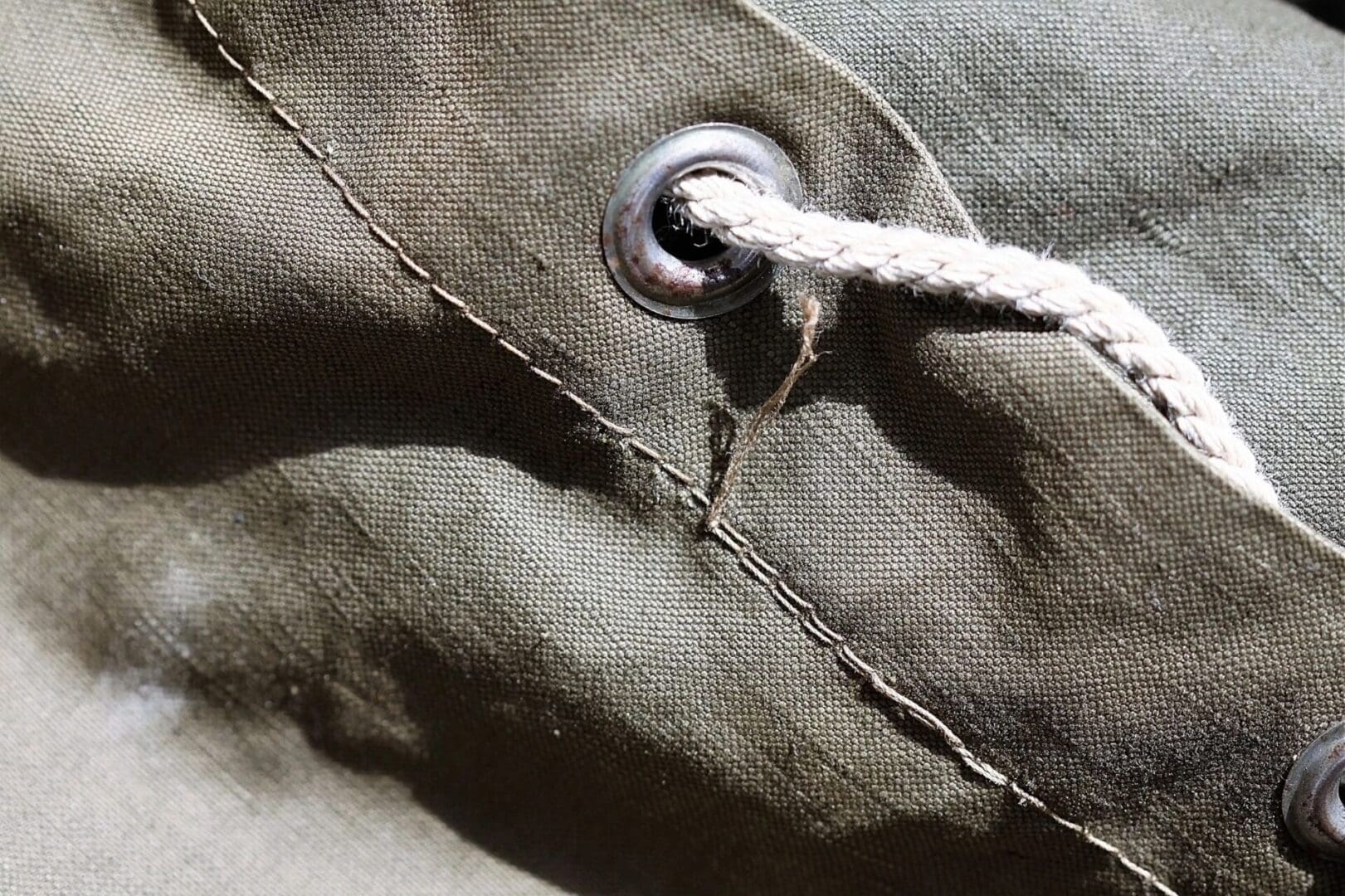 A close up of a knot on a green canvas bag.