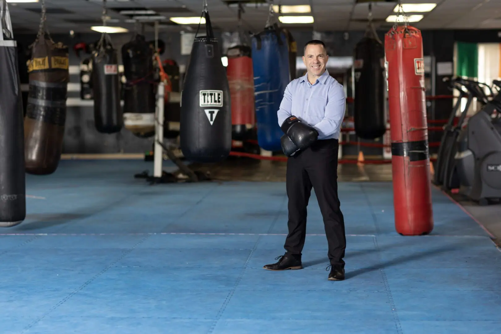 A man standing in front of a boxing ring with punching bags.