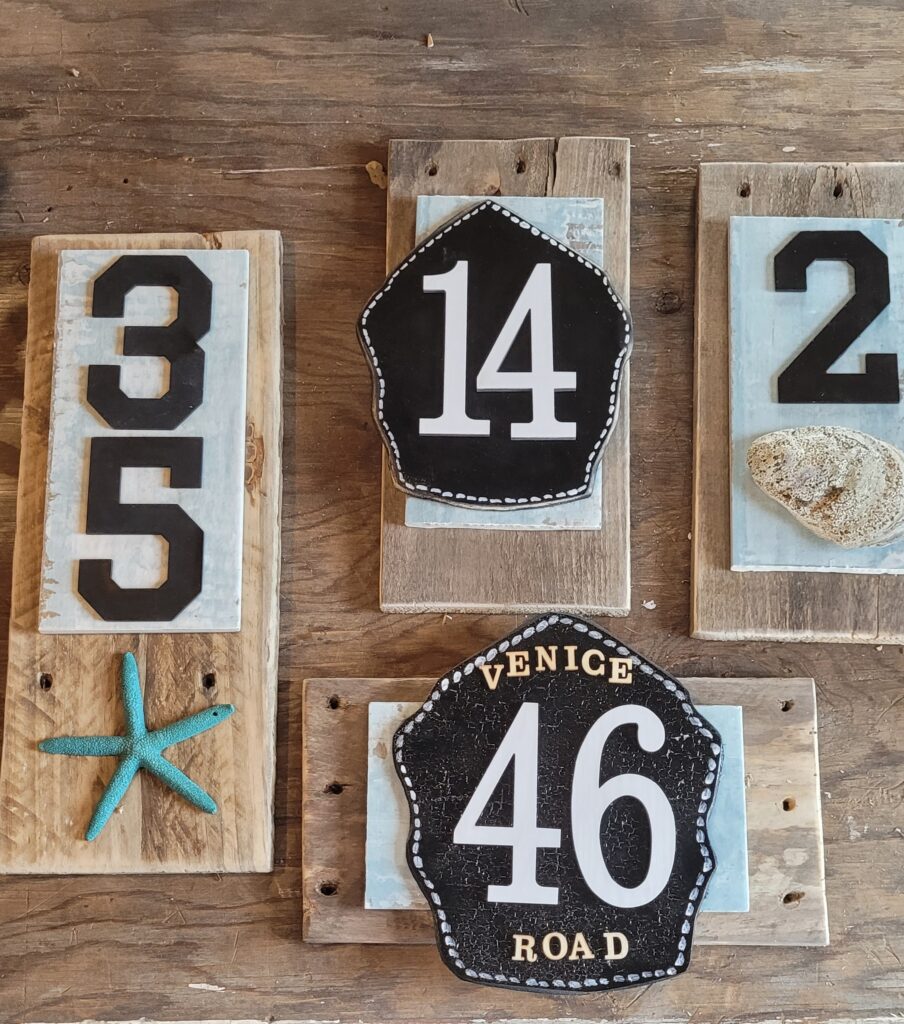 A set of wooden house numbers with starfish and seashells on them.