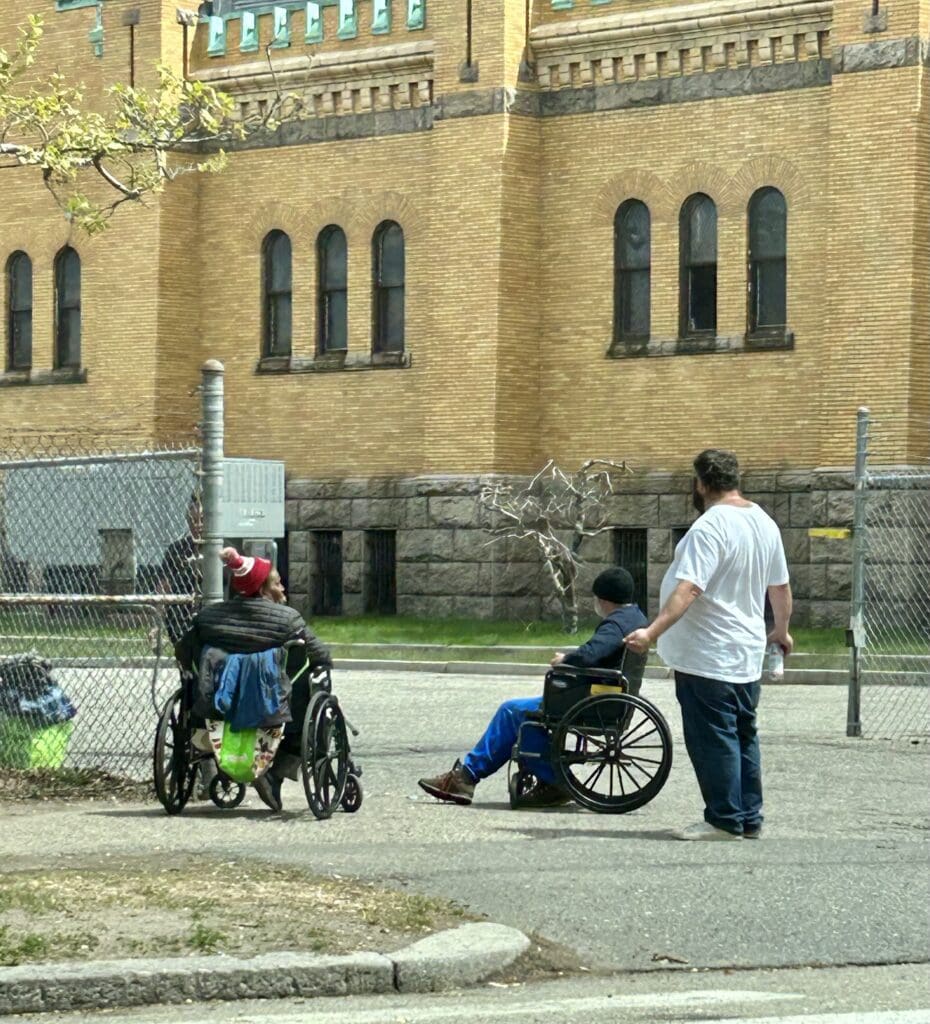 A group of people in wheelchairs in front of a building.
