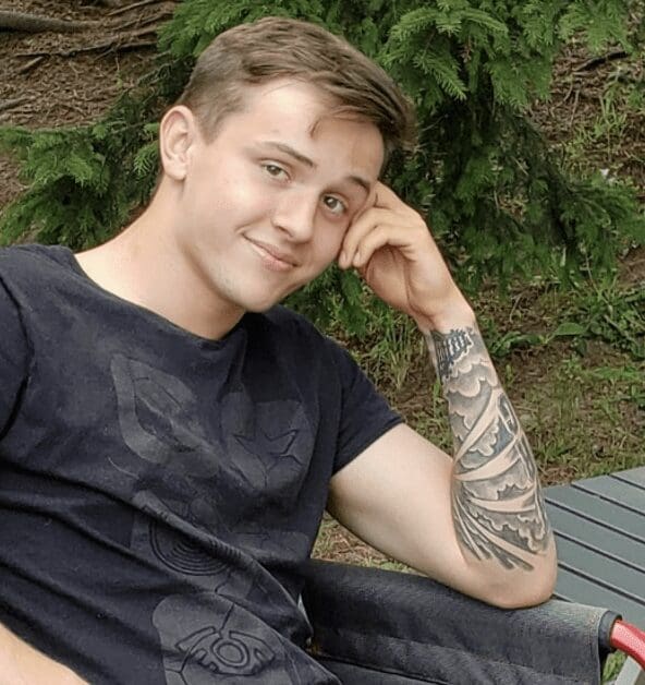 A young man sitting on a lawn chair with AEW tattoos.