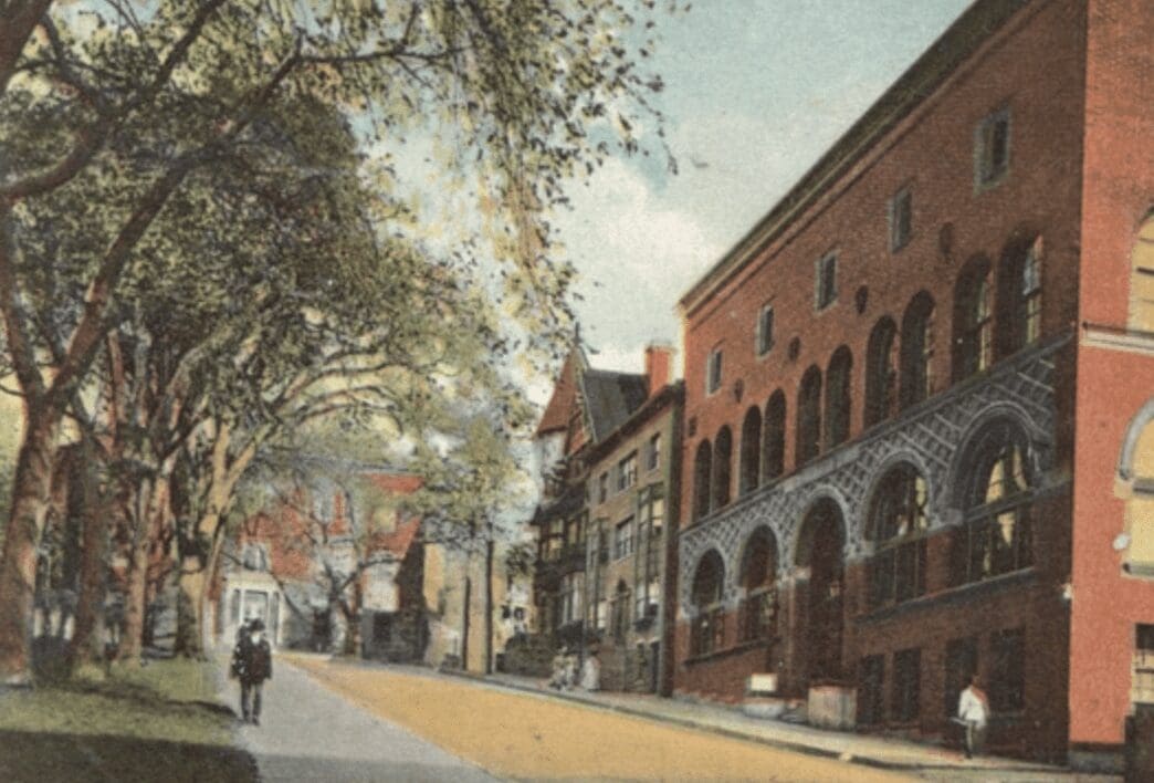 An old postcard shows a street with buildings and trees.