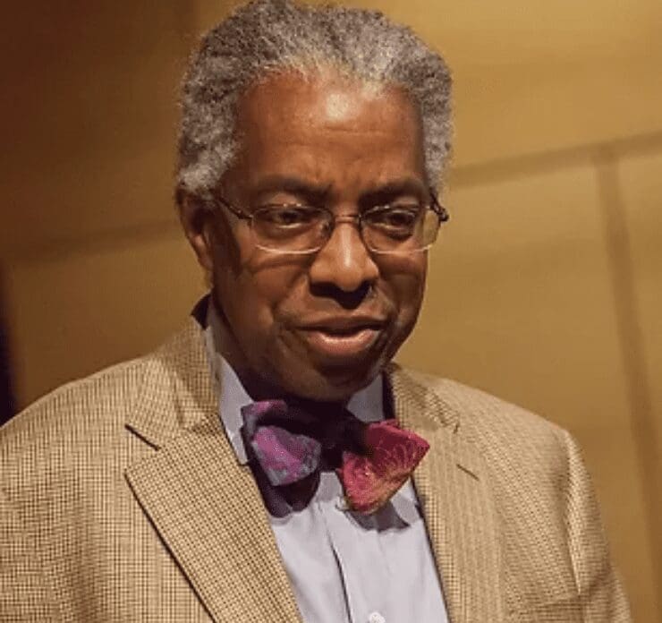 A man of race wearing glasses and a bow tie.