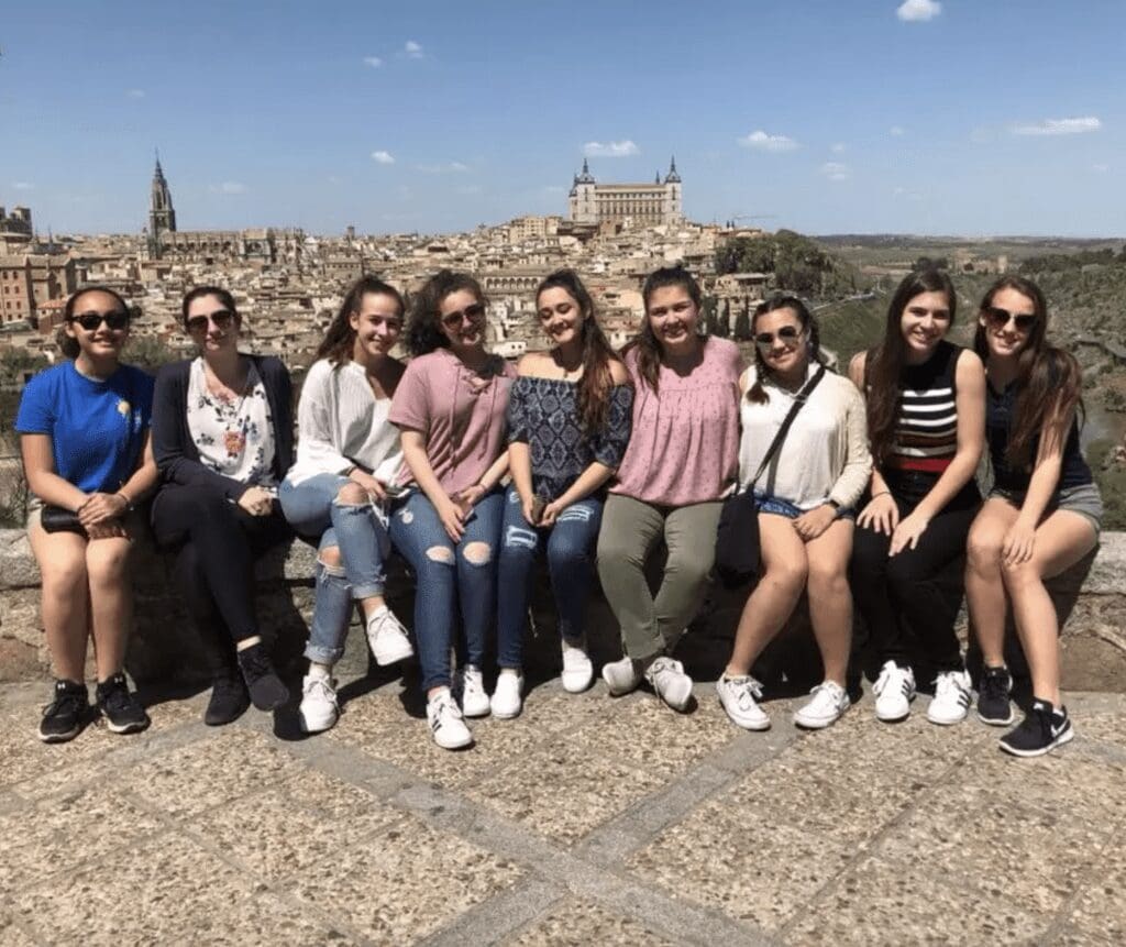 A group of girls posing for a photo in front of a city.