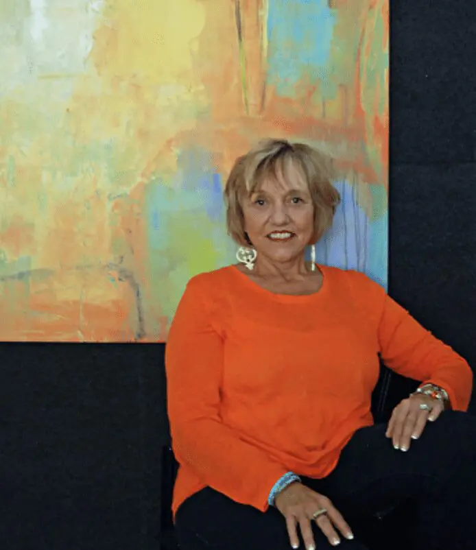 A woman sitting on a chair in front of a painting.