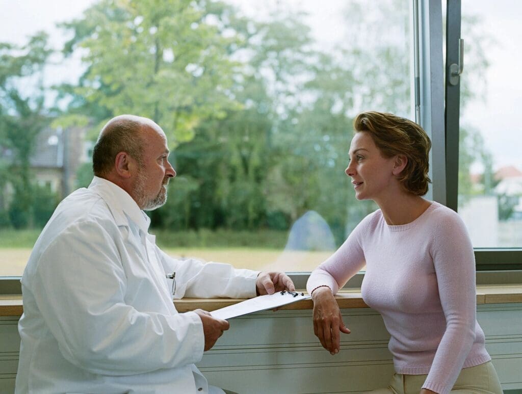 A doctor talking to a woman in front of a window.