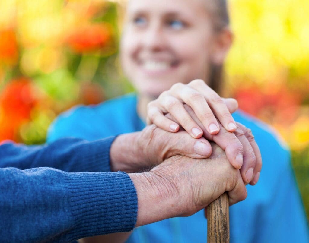 An elderly woman is holding an elderly woman's hand.