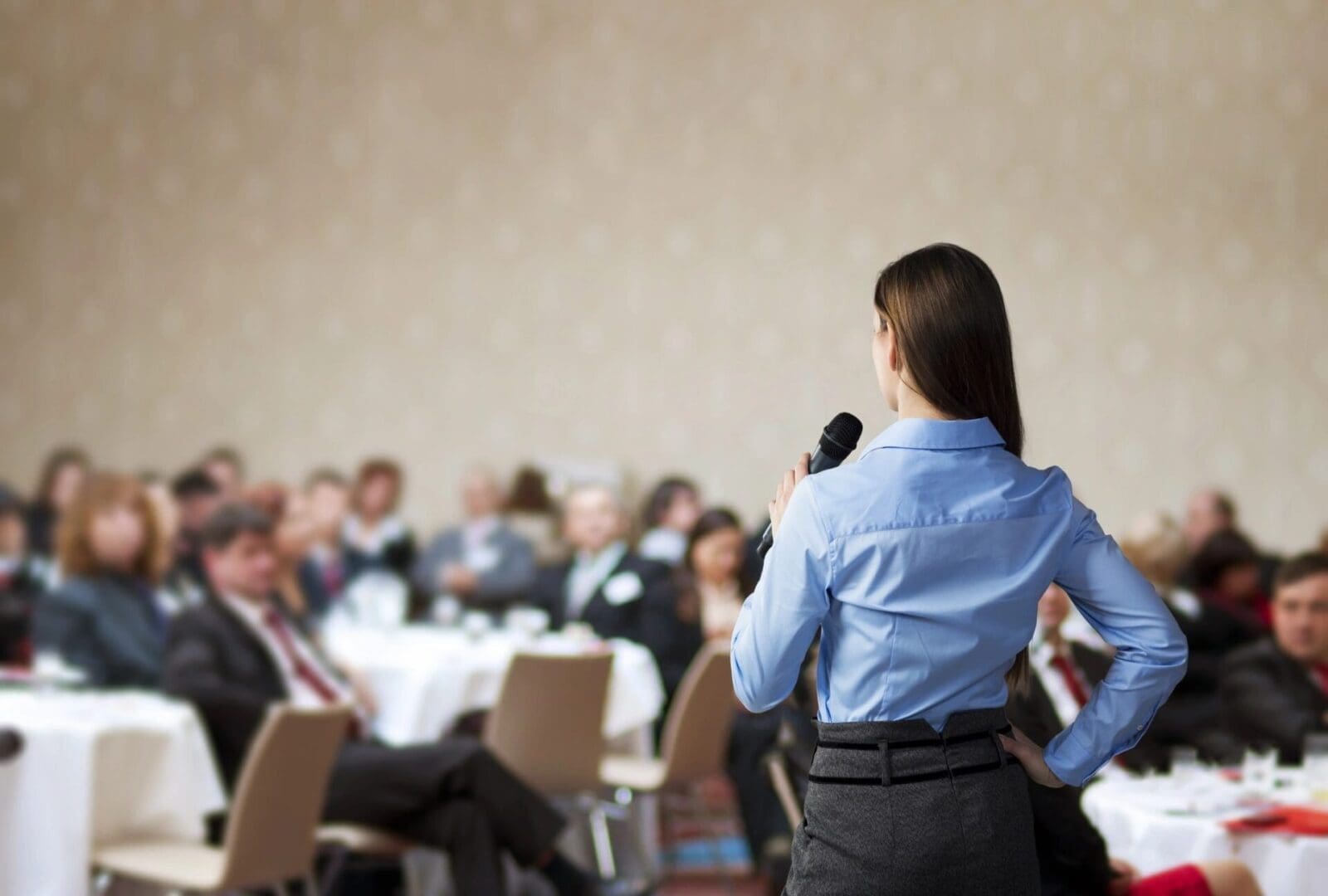 A business woman giving a speech in front of an audience.