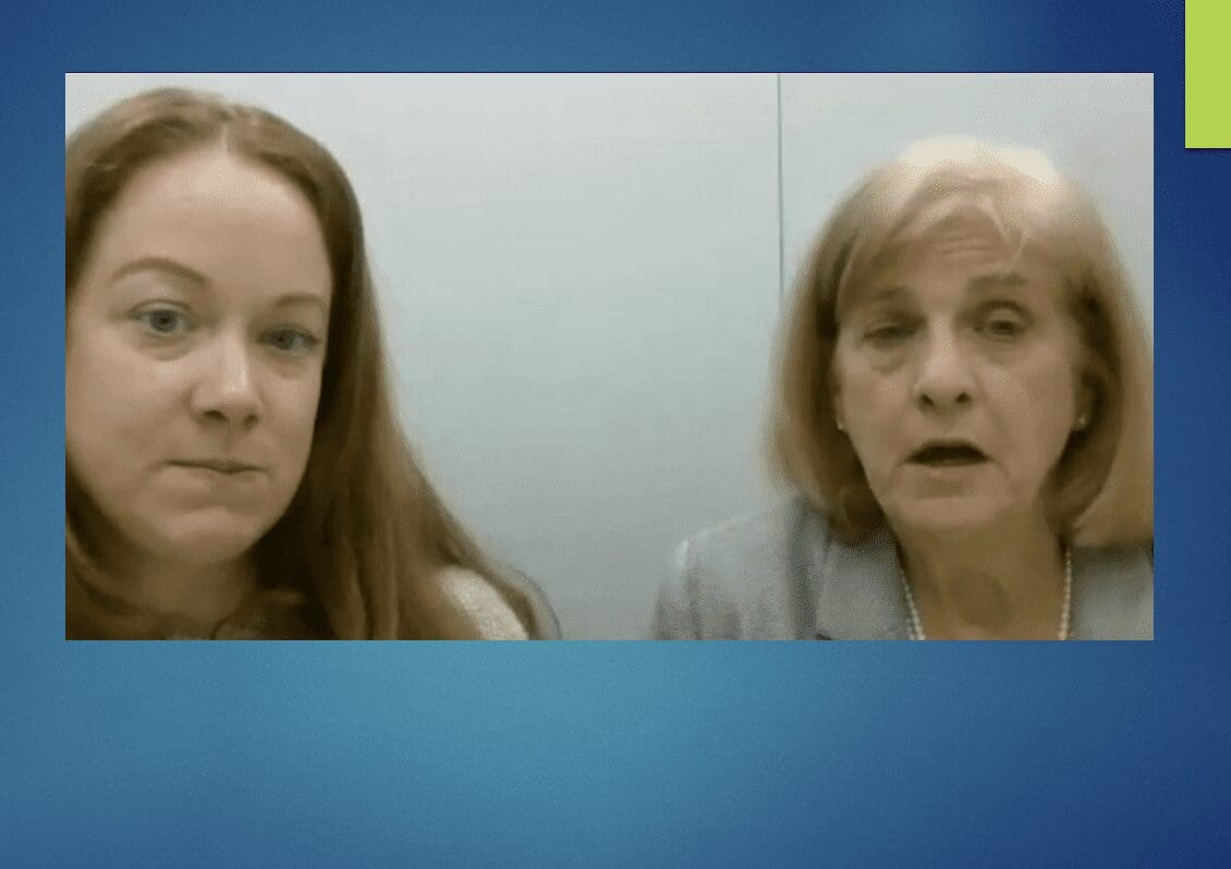 Two women are talking in front of a blue background at a day care in Rhode Island.