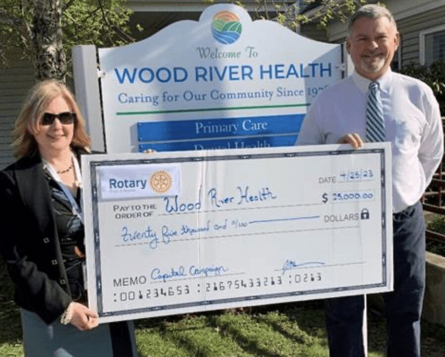 A man and woman holding a check for wood river health.