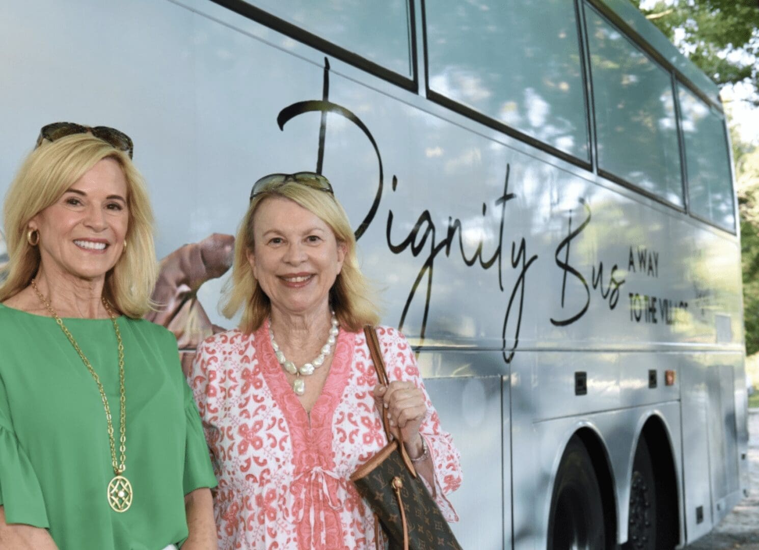 Two women standing in front of a bus.