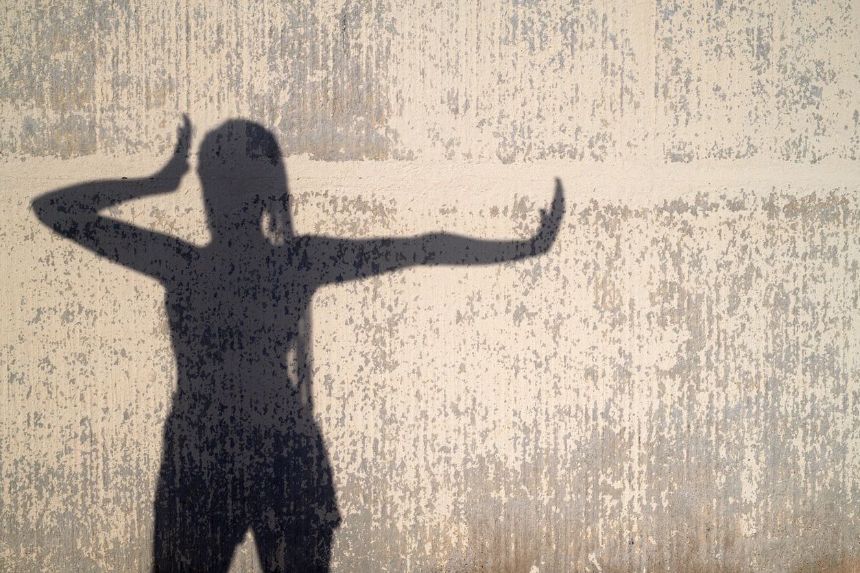 A silhouette of a woman standing in front of a wall.