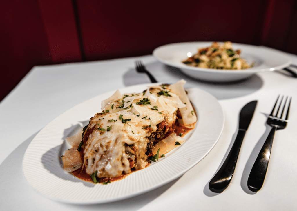 A plate of lasagna and a fork on a table, perfect for indulging in delectable recipes.