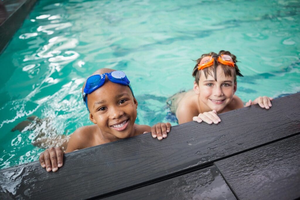 Two boys in swimming goggles smiling at the camera.