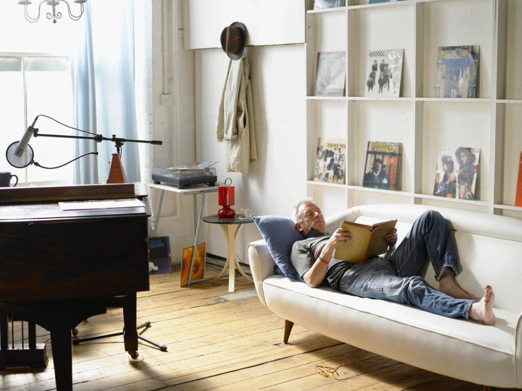 A man laying on a couch in a room with a piano.