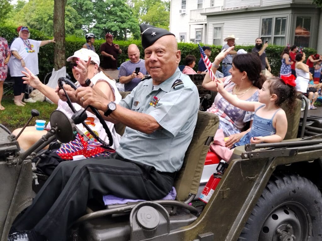 A veteran driving a jeep in a parade.