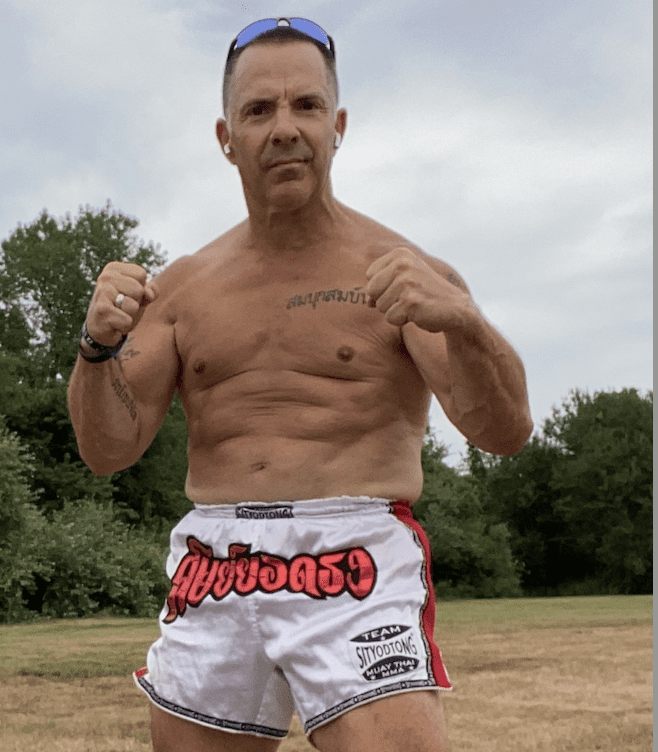 A man in boxing shorts posing in a field.