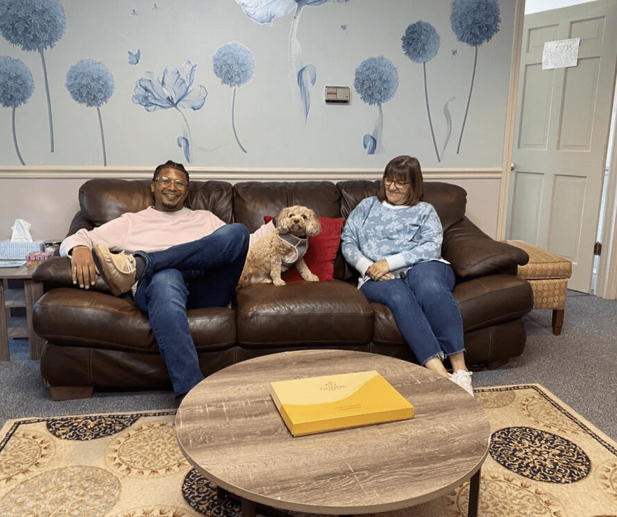 A man and woman sitting on a couch with a dog.